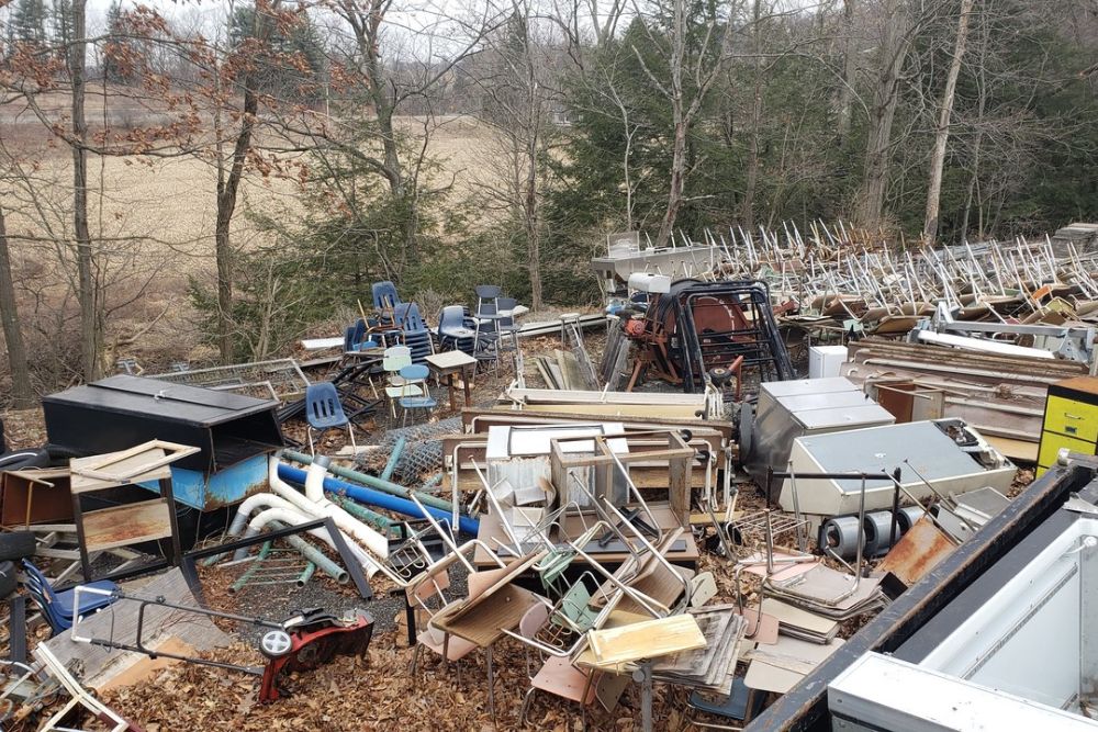 A large pile of discarded furniture and junk in a forested area, emphasizing Seattle's bulk junk removal service offerings.